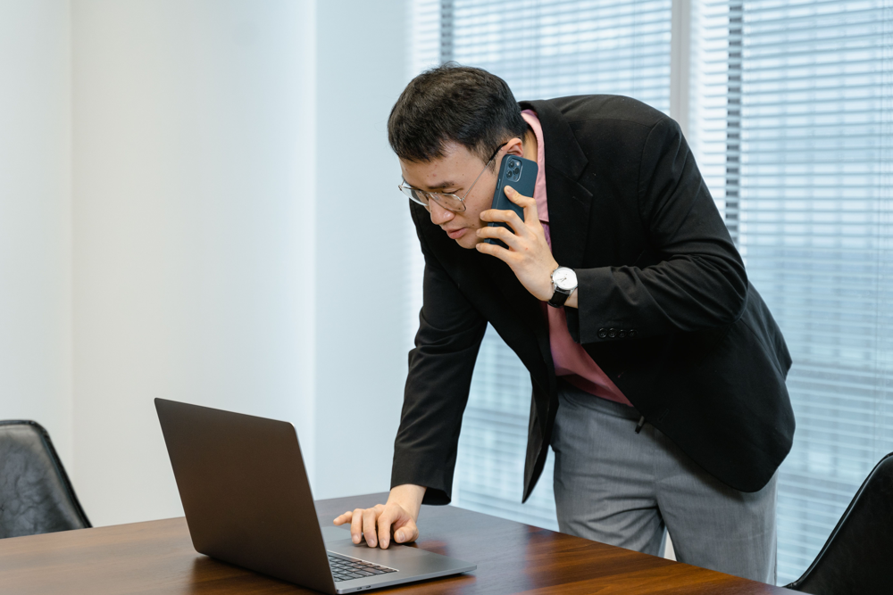 電話しながらパソコンを見る人物